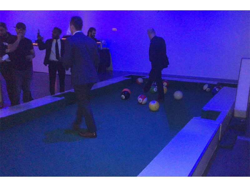 People playing soccer pool at a party.