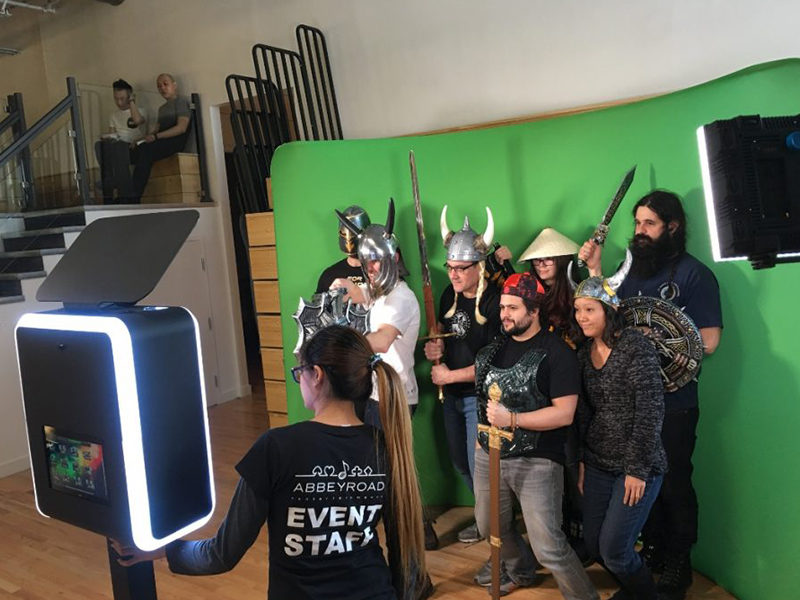 People posing for photo with props on the green screen backdrop.