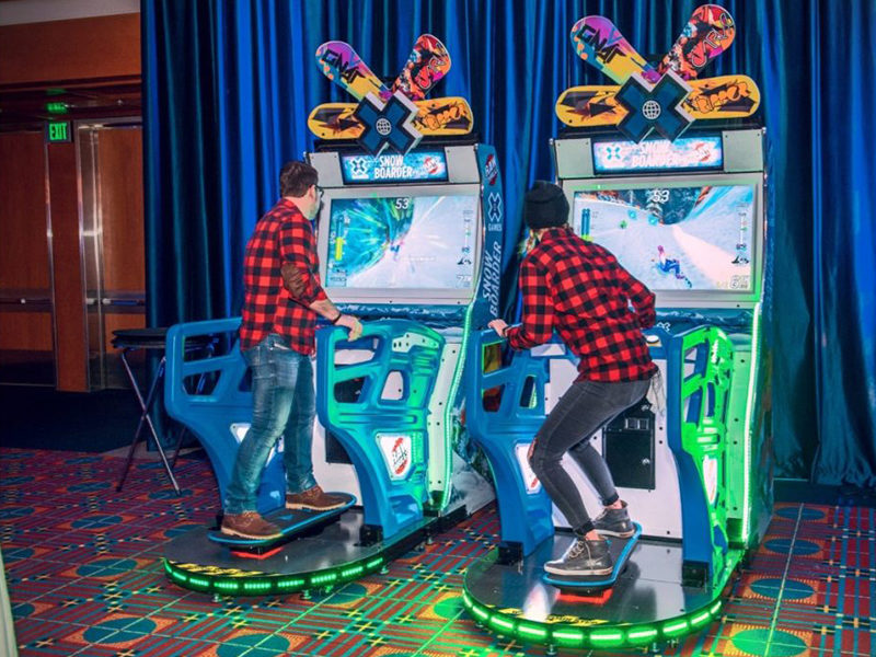 Two men playing the X Games Snowboarder Arcade Rental in Toronto.