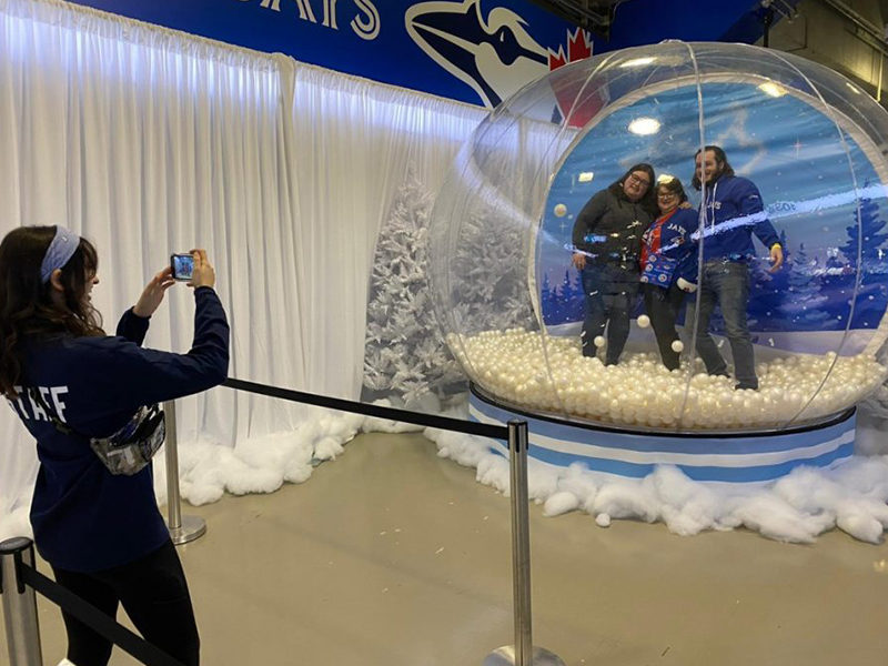 Giant Snow Globe rental with people inside posing for photo.