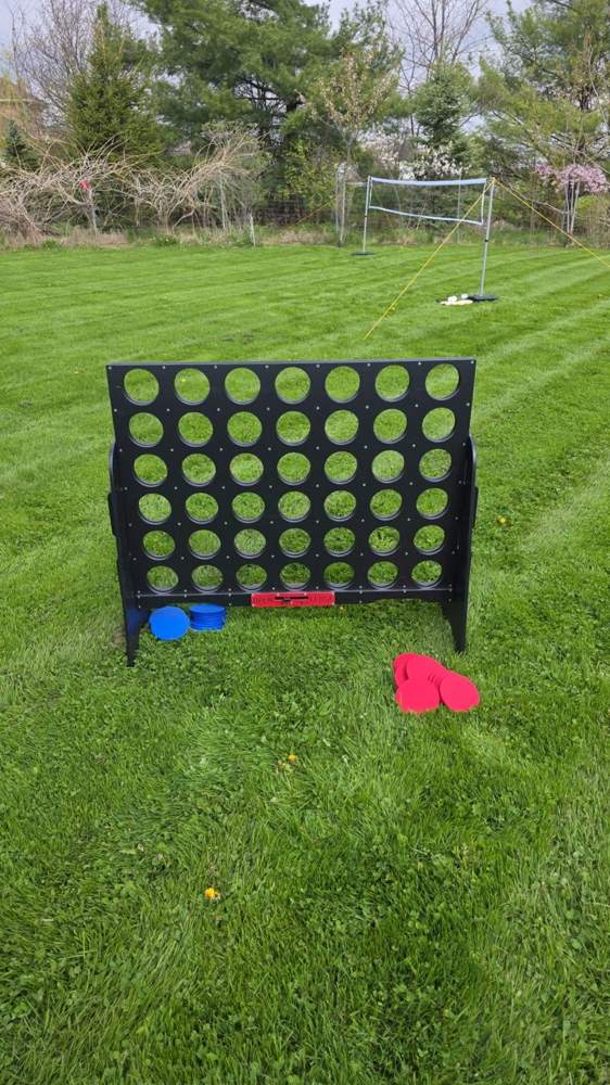 Giant Connect 4 set up on a grass field with a soccer net behind