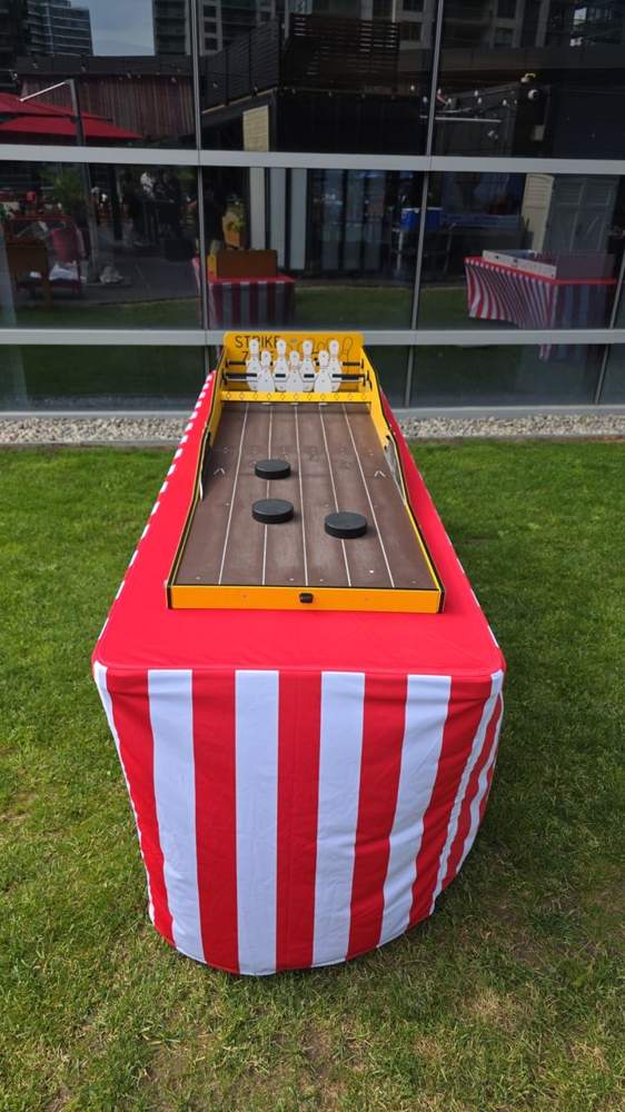 Carnival tabletop bowling game on a striped carnival table on grass