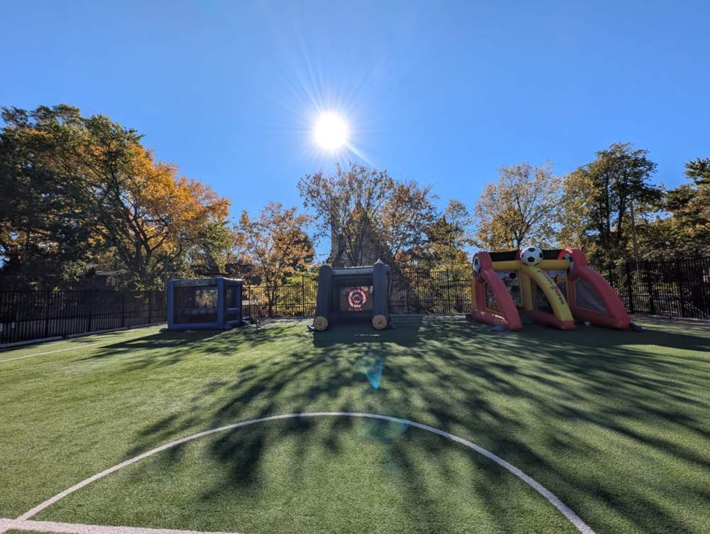 Inflatable soccer, axe throw and archery games on a school turf field